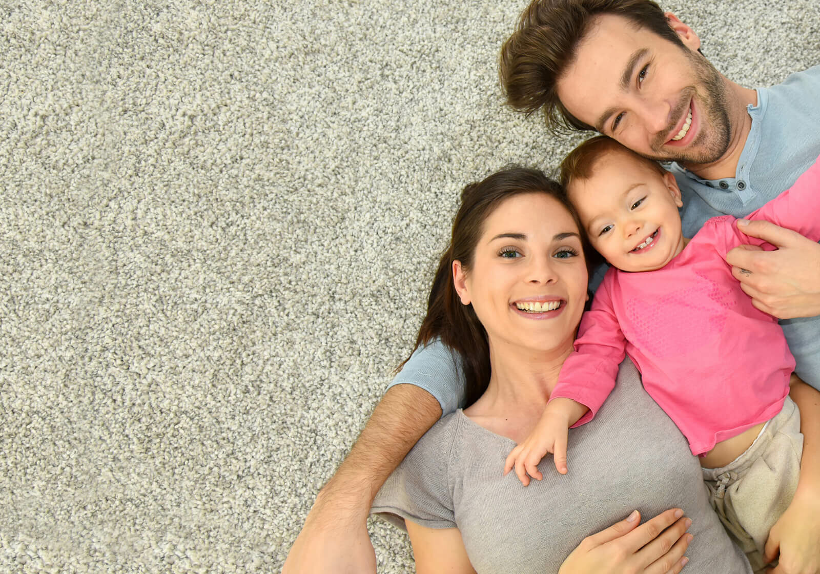 Happy family laying on carpet floor | Gunn Flooring Company